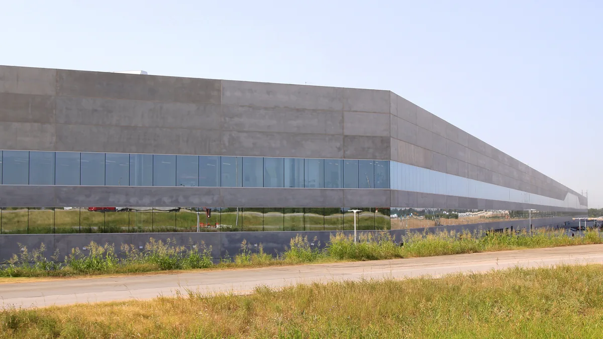 Long concrete Tesla Gigafactory Texas building with a ribbon of glass windows under a clear sky