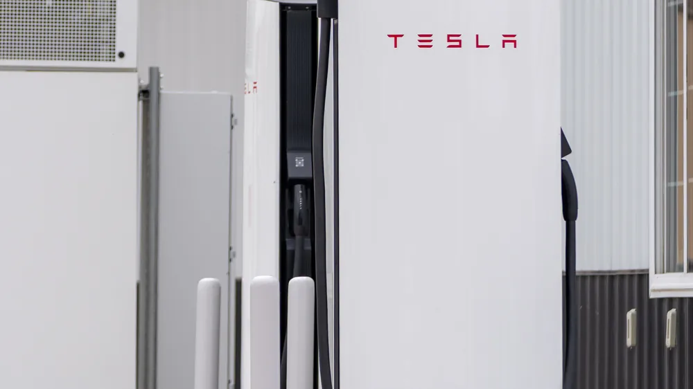 White Tesla Supercharger stall with the charging handle docked in its holster